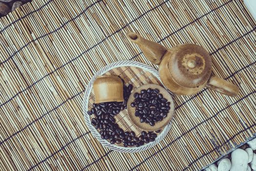 Coffee beans and coffee cup set on bamboo wooden background.Photo in retro color image style, Soft focus.