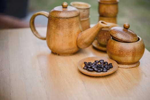 Coffee beans, cup of coffee and teapot on wooden desk. Set of cafe