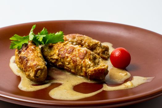 Tree meat rolls decorated with some dressing, greens and tomato