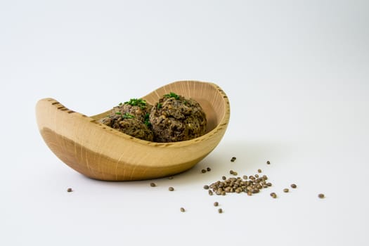 Meat balls in wooden plate decorated with spring onions, isolated on white.