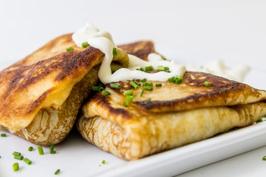 Two pancakes stuffed with meat with sour cream, isolated on white