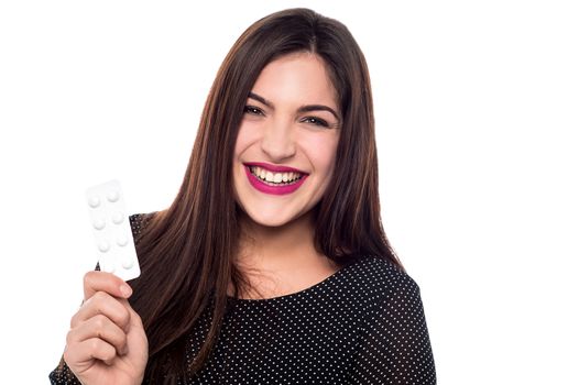 Happy young woman showing strip of pills
