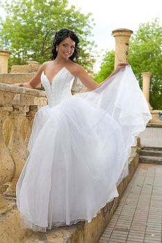 Young dark-haired beautiful woman in a wedding dress in diferent outdoor situations