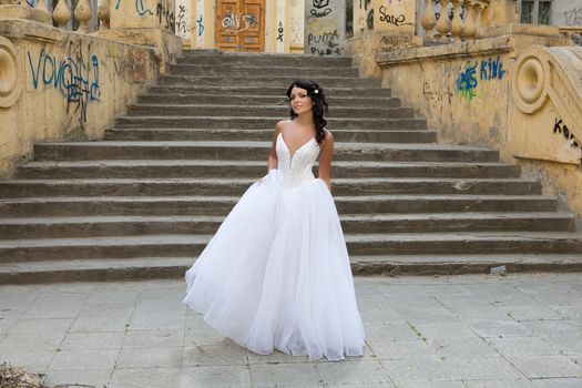 Young dark-haired beautiful woman in a wedding dress in diferent outdoor situations