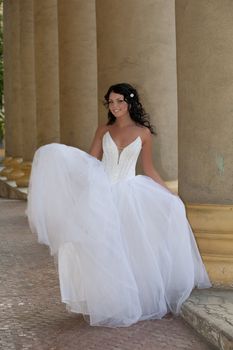 Young dark-haired beautiful woman in a wedding dress in diferent outdoor situations