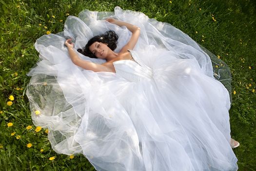 Young dark-haired beautiful woman in a wedding dress in diferent outdoor situations