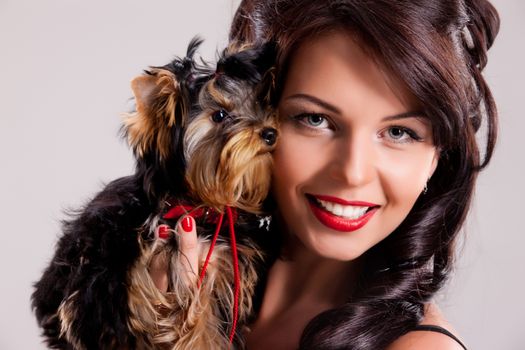 Young beautiful brunette woman in a black dress with a Yorkshire terrier