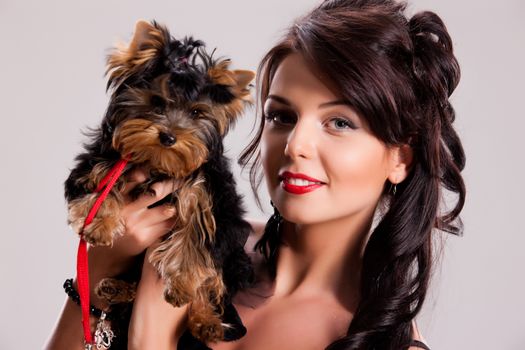 Young beautiful brunette woman in a black dress with a Yorkshire terrier