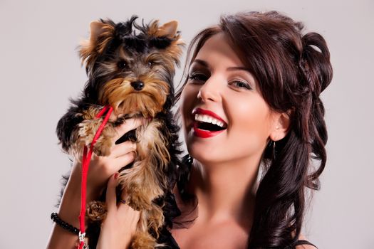 Young beautiful brunette woman in a black dress with a Yorkshire terrier