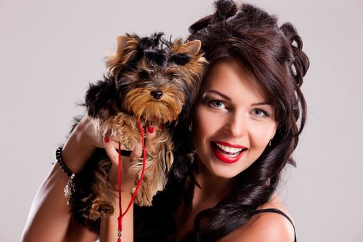 Young beautiful brunette woman in a black dress with a Yorkshire terrier
