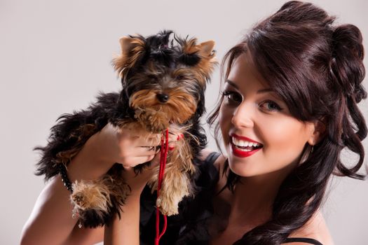 Young beautiful brunette woman in a black dress with a Yorkshire terrier