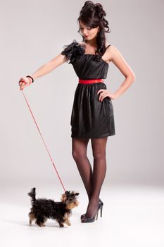 Young beautiful brunette woman in a black dress with a Yorkshire terrier