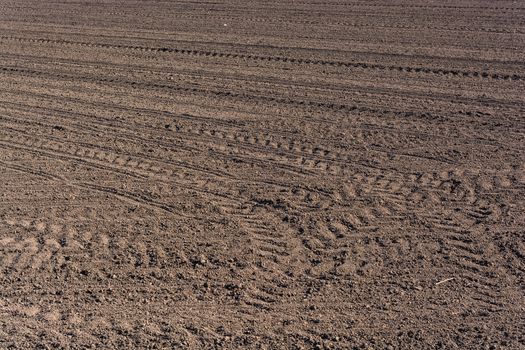 Plowed  fertile soil with tractor traces - cultivated land