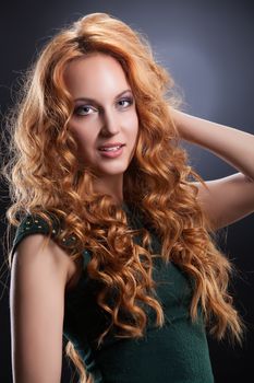 Young beautiful red- haired woman on a studio background