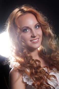 Young beautiful red- haired woman on a studio background