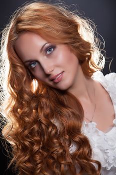 Young beautiful red- haired woman on a studio background