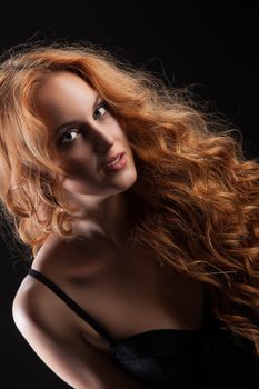 Young beautiful red- haired woman in a black lingerie sitting on an old Viennese chair