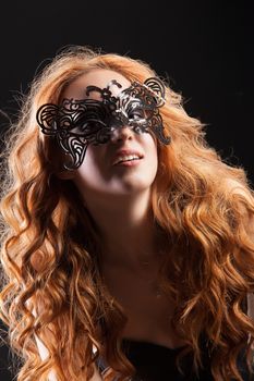 Young red- haired woman in a black lingerie on a studio background
