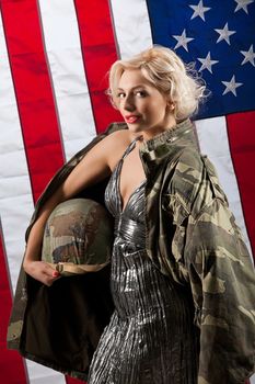 Young beautiful woman in a military jacket holding helmet and american flag