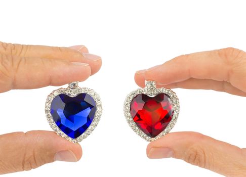 Fingers of man and woman holding blue and red jewelry hearts isolated on white background