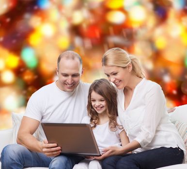 family, childhood, holidays, technology and people concept - smiling family with laptop computer over red lights background