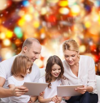 family, holidays, technology and people - smiling mother, father and little girls with tablet pc computers over red lights background