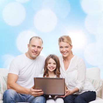 family, childhood, holidays, technology and people concept - smiling family with laptop computer over blue lights background