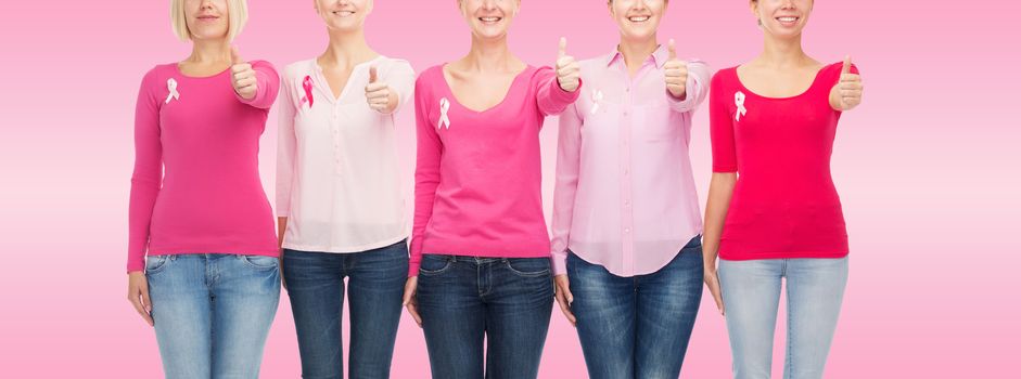 healthcare, people, gesture and medicine concept - close up of smiling women in blank shirts with breast cancer awareness ribbons over pink background