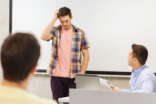 education, high school, technology and people concept - students and teacher with notepad, laptop computer in classroom