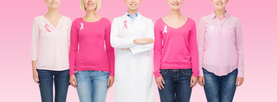 healthcare, people and medicine concept - close up of smiling women in blank shirts with breast cancer awareness ribbons over pink background