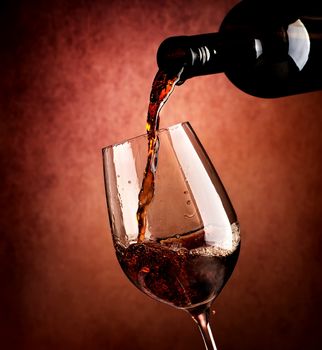 Wine pouring in wineglass on a brown background