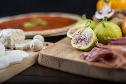 Rustic home made pizza on wooden table with fresh ingredients and cheese