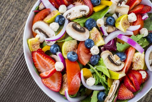 Detail of fresh colorful salad with healthy ingredients, berries, figs, greens and feta cheese