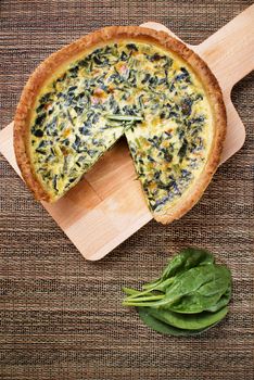 Freshly baked spinach quiche over wood tray