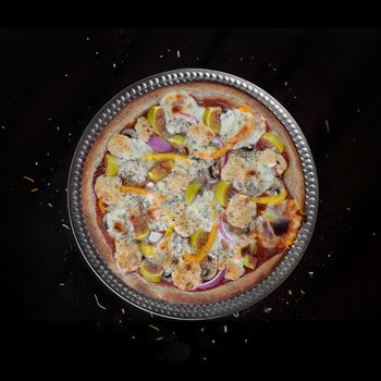 Fresh baked home made veggie pizza with figs and feta cheese over black background