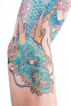 A detailed shot of a blue/green dragon tattoo in Japanese style on the forearm, elbow and bicep of a white male isolated on a white background.