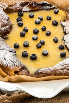 eclair cake in casserole dish with blueberry on wood table