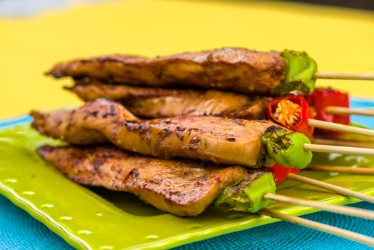 Satay Chicken on green plate decorated with red and green pepper