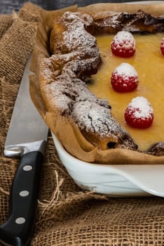 eclair cake in casserole dish with raspberry on wood table