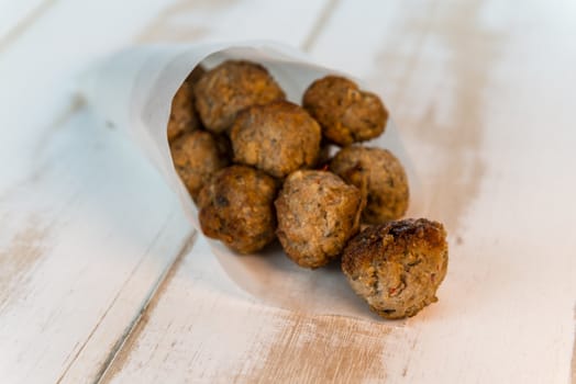 meatballs in a white paper bag on white wooden table