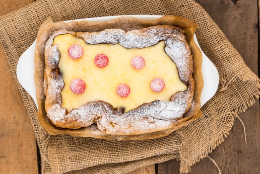 top view of eclair cake in casserole dish with raspberry on wood table