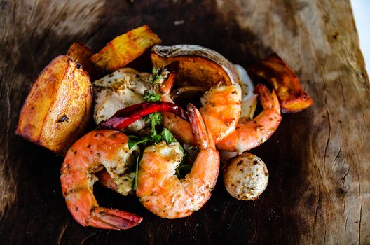 fresh shrimps served on a wood plate with garlic onion chili and fried potatoes