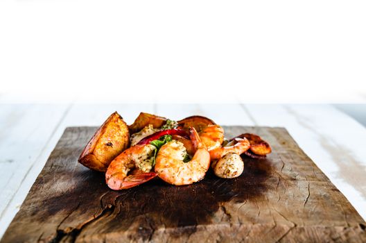 fresh shrimps served on a wood plate with garlic onion chili and fried potatoes