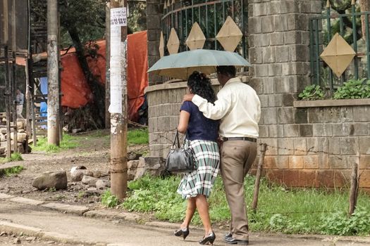 Addis Ababa - July 26: A couple walk holding their umbrella in the drizzling rain on a typical winter day during the rainy season on June 26, 2015 in Addis Ababa, Ethiopia.