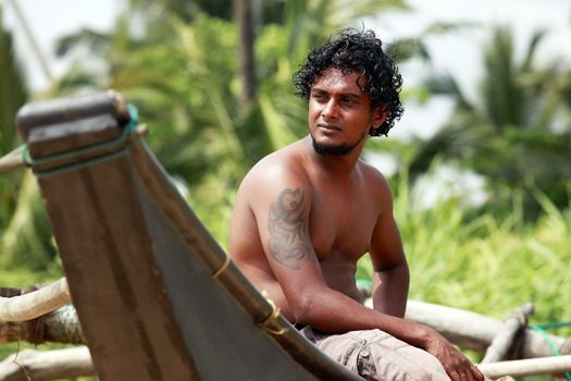 The young man sitting by a boat. Sri Lanka