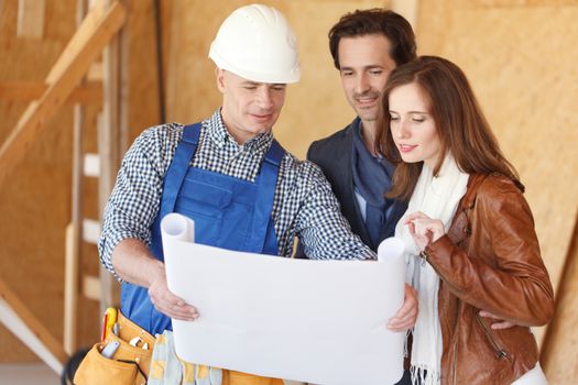 foreman shows house design plans to a young couple