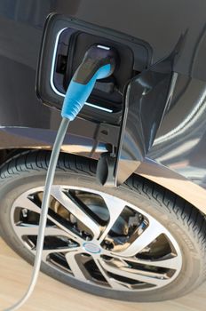 Modern electric ecologically pure car plugged in to power supply at charging station