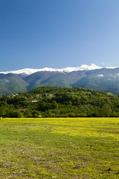 Mountains are covered with snow and the wood and surrounded with clouds