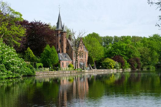Flemish style castle reflecting in Minnewater lake in Bruges, Belgium