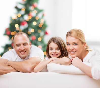 family, childhood, holidays and people - smiling mother, father and little girl over living room and christmas tree background